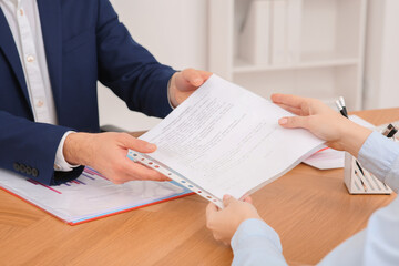 Businesspeople working with documents at wooden table in office, closeup