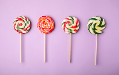 Many colorful lollipops on violet background, flat lay