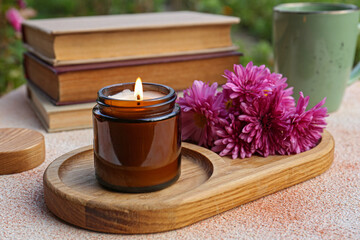 Obraz na płótnie Canvas Burning candle and chrysanthemum flowers on beige textured table, closeup