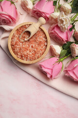 Aromatic sea salt and beautiful roses on pink marble table, top view. Space for text