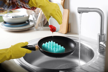 Woman using cleaning product for washing frying pan in sink indoors, closeup
