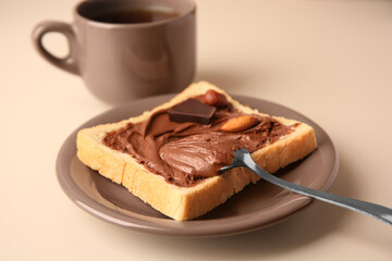 Tasty toast with chocolate paste and cup of tea served on light table