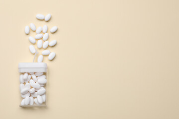 Tasty dragee candies and container on yellow background, flat lay. Space for text