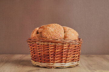 Wicker basket of fresh buns with sesame seeds on wooden table