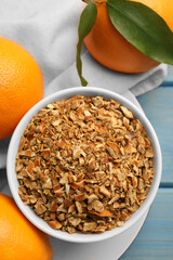 Bowl of dried orange zest seasoning and fresh fruits on blue wooden table, flat lay
