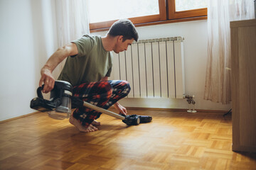 a man vacuums the floor in an apartment