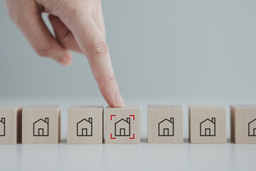 Hand point to house icon with focus frame on wood block. Real estate, Property investment and asset management concept. Decision to choose best property with your right. Choosing suitable housing.