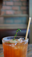 Selective focus a glass of refreshing cold soft drink lemon iced tea in ice cube with paper straw, decorated with sliced lime and thyme branches, summer drink