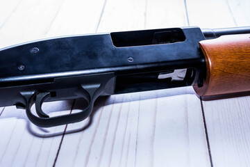 A 12 gauge shotgun with an opened chamber on white wooden background 