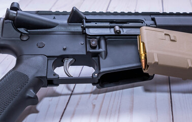 An AR15 rifle chambered in 223 caliber with a loaded magazine next to it on a white wooden background