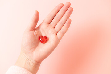 Woman hand holding red glass heart.