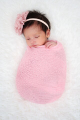 happy newborn baby girl sleeping in cloth wrap blanket on bed.