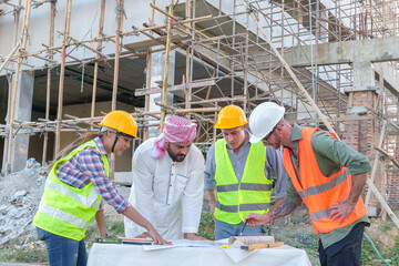 Diverse team of professionals using tablet computers on construction site. Real estate construction...