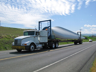 Fototapeta na wymiar A truck carries one blade of a wind turbine to its final destination.