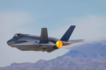 Extremely close view of a F-35 Lightning II against the Nevada hills, with afterburner on - obrazy, fototapety, plakaty