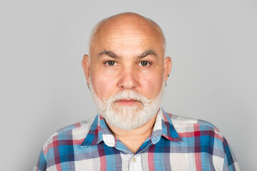 Older grandfather, grandpa pensioner, retiree concept. Portrait of an bald old mature senior man with grey beard in shirt isolated on gray studio background.