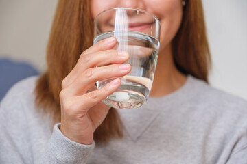 Closeup image of a young woman holding a glass of water to drink