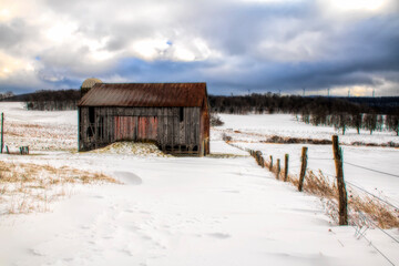 Old barn in middle field in the snow on wintry day