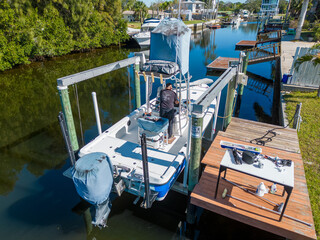 Fototapeta na wymiar Tower boat with covers on boat lift with deck dock with person on board in Tampa Florida from aerial drone
