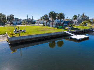 Concrete sea wall on plot of land in Gulf of Mexico Canal peninsula with a white floating dock