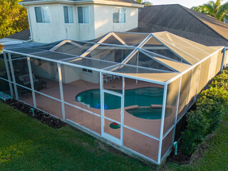 Pool and patio screen enclosure connected to Florida house roof with sunset