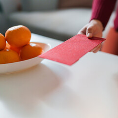 Asian Woman giving red envelope for Lunar New Year celebrations. Hand hold red packet thankful...