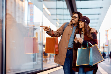 Happy couple in love enjoys in window shopping in city.