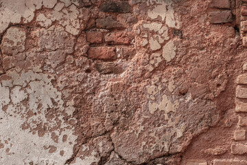 Abandoned old brick wall with damaged plaster and cracks
