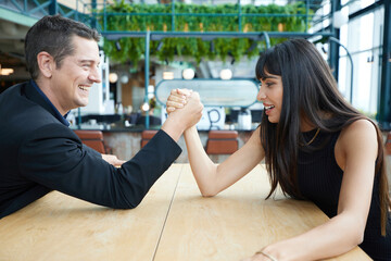 man and woman arm wrestling competition on the table
