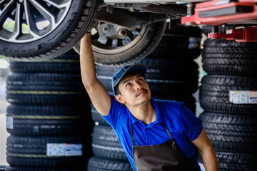 Fototapeta na wymiar Auto mechanic repairman using a socket wrench working auto suspension repair in the garage, change spare part, check the mileage of the car, checking and maintenance service concept.