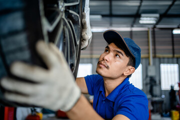 Auto mechanic repairman checking tire condition and suspension in the garage changes spare parts, checks the mileage of the car, checking and maintenance service concept.