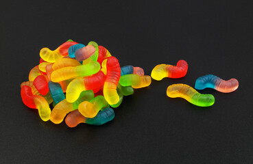 Heap of gummy worms on black background.