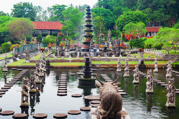 Ancient water palace Tirta Gangga with fountains, natural pools, path in fish pond with statues of...