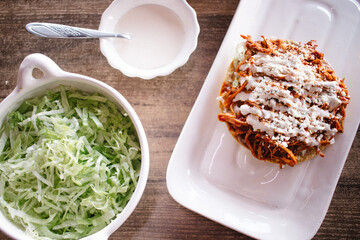 Tostada de tinga de pollo con crema, queso y lechuga 