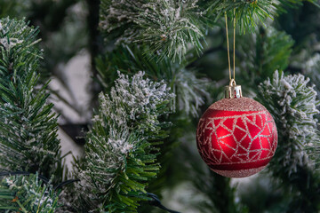 Close up of red bauble hanging from Christmas tree.