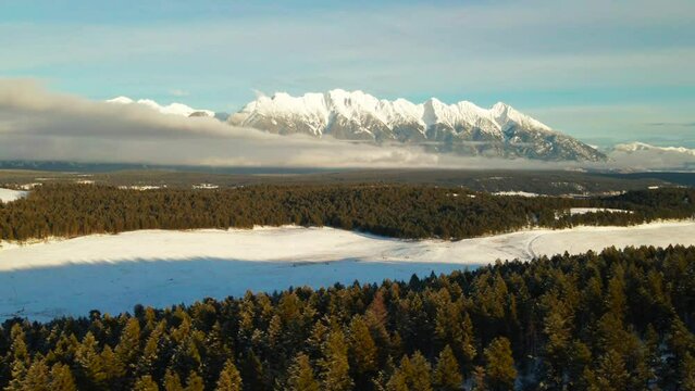 Winter's Majestic Scene: A Sunset Aerial View of Snowcapped Mountains and a Snowy Forest in British Columbia
