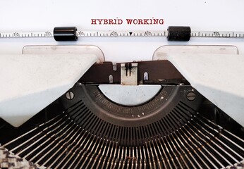 Vintage typewriter with red typed text HYBRID WORKING, means flexible approach combines working in...