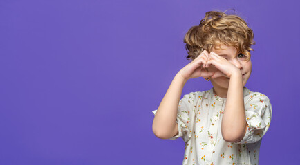 Cute caucasian girl child elementary school making hands in heart shape over purple blue background banner. Health insurance, donation charity, world heart day, appreciation, world children day