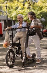 Naklejka premium elderly couple do the shopping with electric scooter - mature couple use electric scooter to circulate around the city -