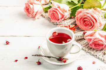 Obraz na płótnie Canvas The concept of romantic tea. Wrapped gift, hibiscus tea, a bouquet of delicate roses, sweets