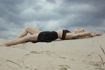 Sensual bare lady lying on beach scenic photography. Picture of person with overcast sky on background. High quality wallpaper. Photo concept for ads, travel blog, magazine, article