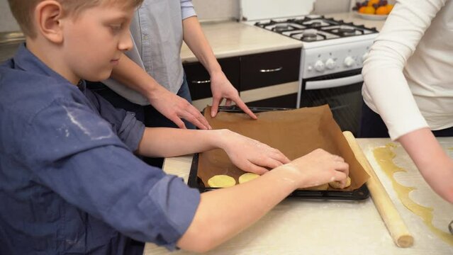 A teenage boy puts circles of dough on a baking sheet.
