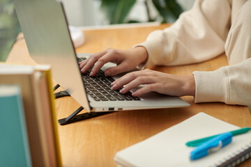 Closeup image of woman working on laptop, answering e-mails or filling documents