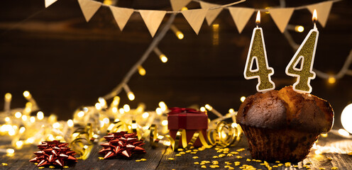 Number 44 golden festive burning candles in a cake, wooden holiday background. forty four years from the date of birth. the concept of celebrating a birthday, anniversary, holiday. Banner.
