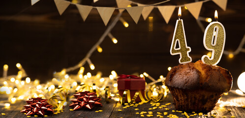 Number 49 golden festive burning candles in a cake, wooden holiday background. forty-nine years from the date of birth. the concept of celebrating a birthday, anniversary, holiday. Banner.