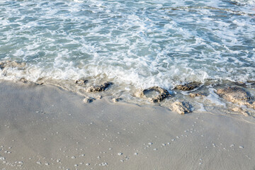 Sandy beach with foam from the wave. The beauty of nature and relaxation. Space for text. Background.