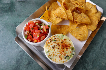 Salsa dip and baked spinach with cheese served with chips at top view