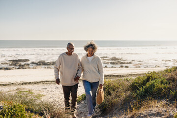 Cheerful elderly couple leaving the beach after a picnic