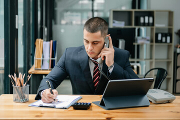 Business oman Talking on the phone and using a laptop with a smile while sitting at modern office