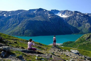 Fototapeta premium Scenic Besseggen trail with two girl taking photo, in Jotunheimen, Norway - the most beautiful trekking trail in Norway